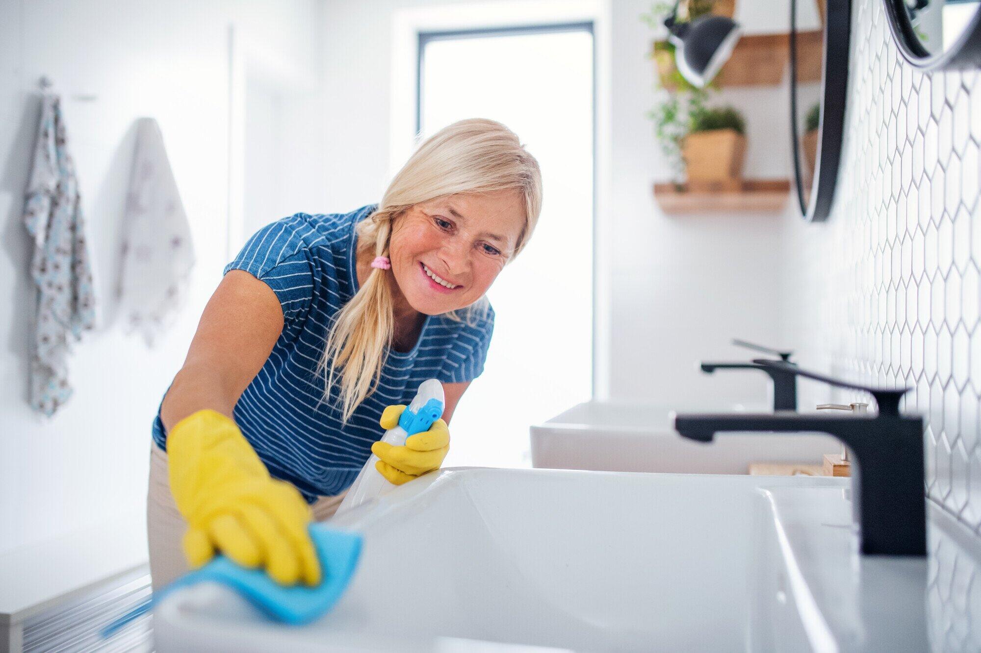 Senior woman with gloves clean